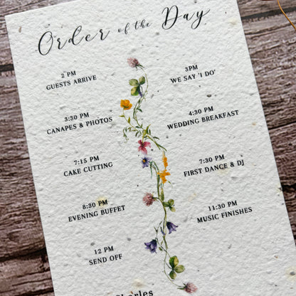 Wedding order of the day card with spring flower design on a wooden surface