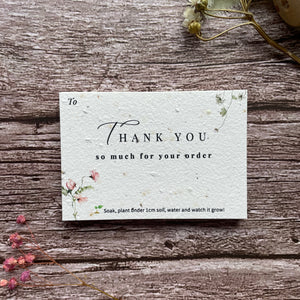 Seed paper thank you card with 'Thank you for your order' message on a wooden surface with flowers.