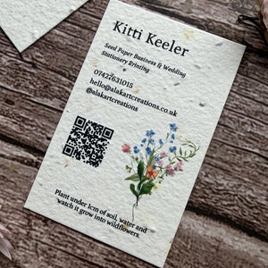 Seed paper business card with floral design and QR code on a wooden surface