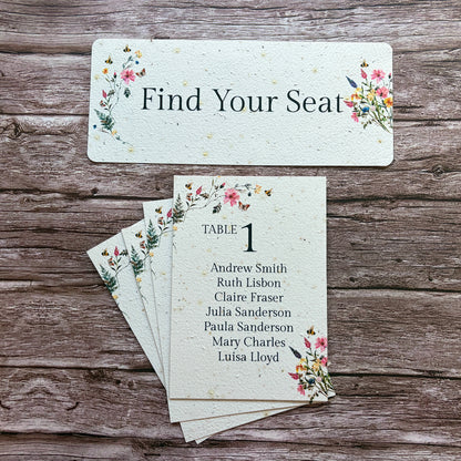 Pink meadow plantable sable seating cards with floral designs on a wooden surface