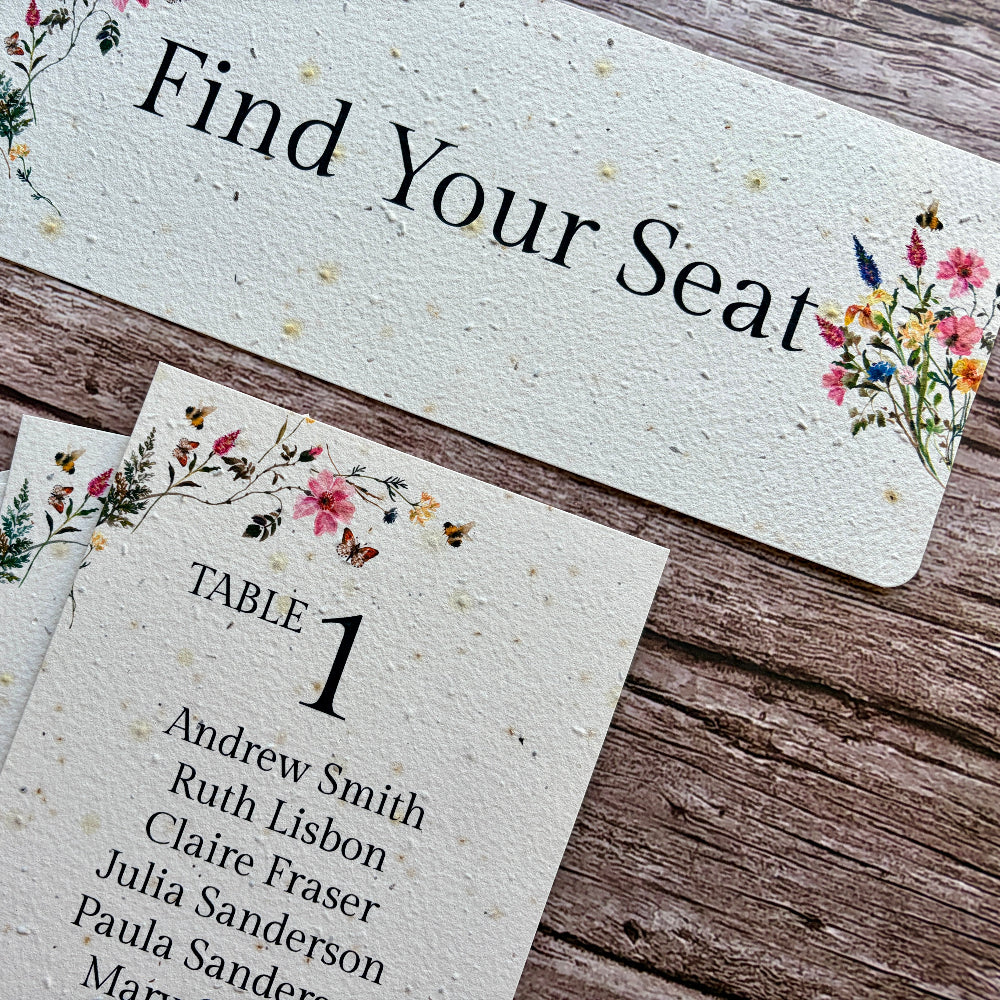 Plantable seating arrangement cards with floral designs on a wooden surface