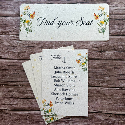 Plantable yellow meadow seating arrangement cards with floral designs on a wooden surface