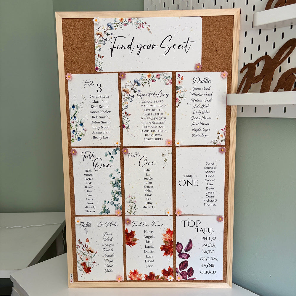 plantable seed paper wedding seating plan on a wooden cork board with flower shaped pins