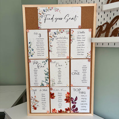 plantable seed paper wedding seating plan on a wooden cork board with flower shaped pins