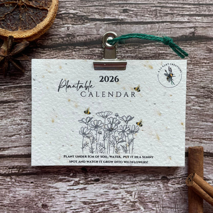2026 calendar card with nature-themed design on a wooden surface with cinnamon sticks and dried oranges.