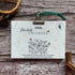 2026 calendar card with nature-themed design on a wooden surface with cinnamon sticks and dried oranges.