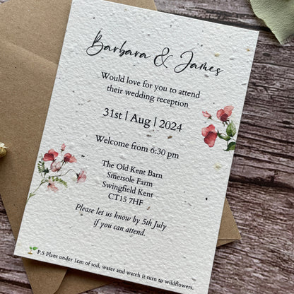 Seed Paper Evening Wedding invitation card with floral designs on a wooden surface