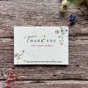 Plantable thank you card with floral design on a wooden surface