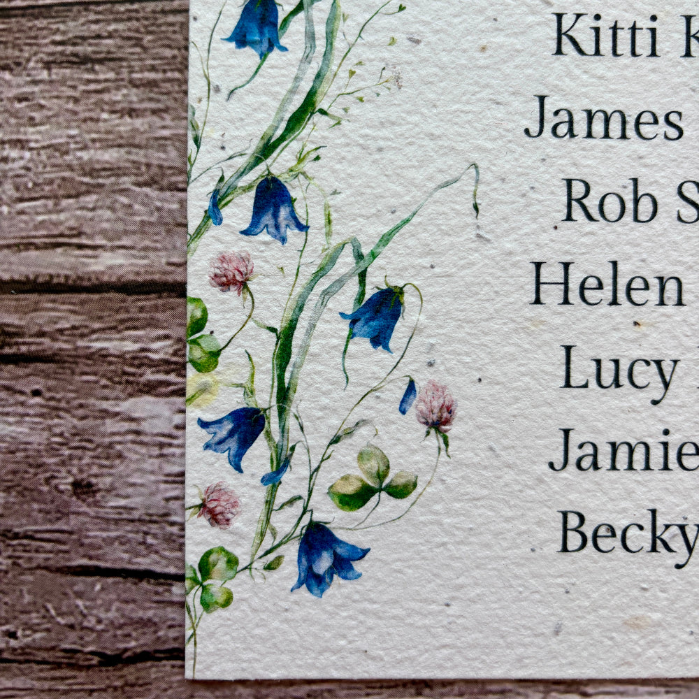 plantable seed paper seating plan for wedding with bluebells design on a wooden background