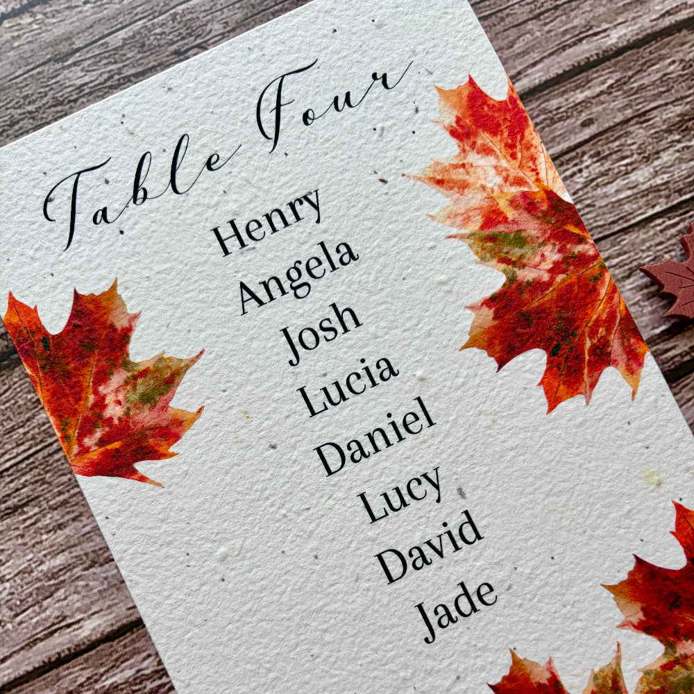 Table assignment plantable card with names and autumn leaf design on a wooden surface