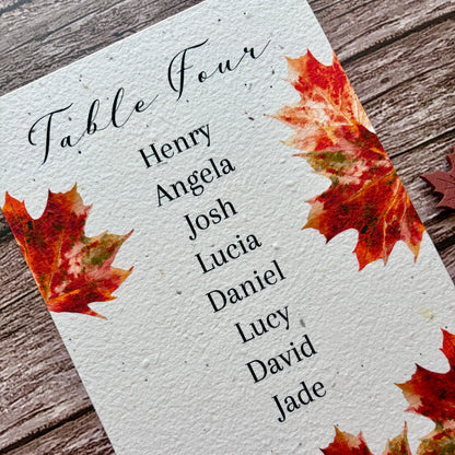 Table assignment plantable card with names and autumn leaf design on a wooden surface