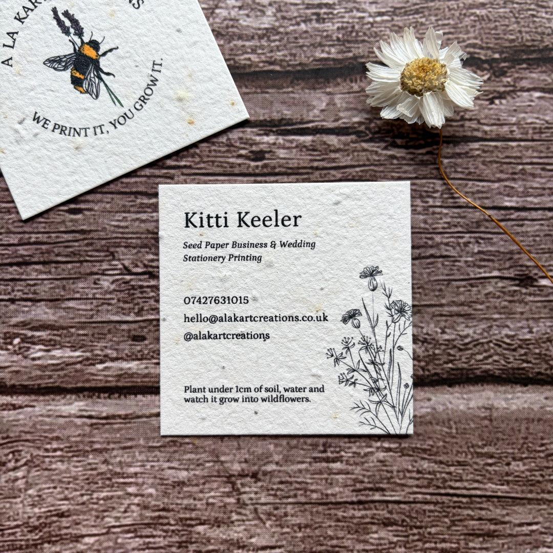 square seed paper business cards on wooden surface with cornflower design