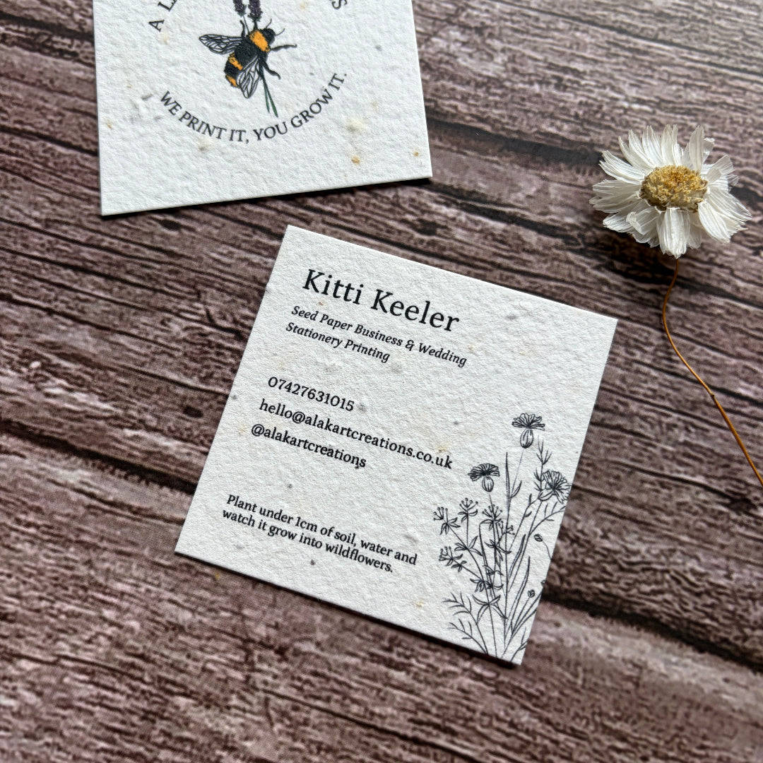 square seed business cards with cornflower design on wooden suraface
