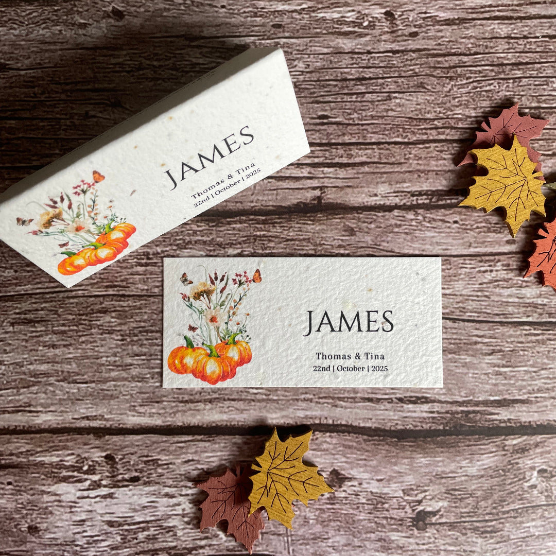 Autumn wedding seed paper name cards with pumpkins and wildflowers on a wooden background