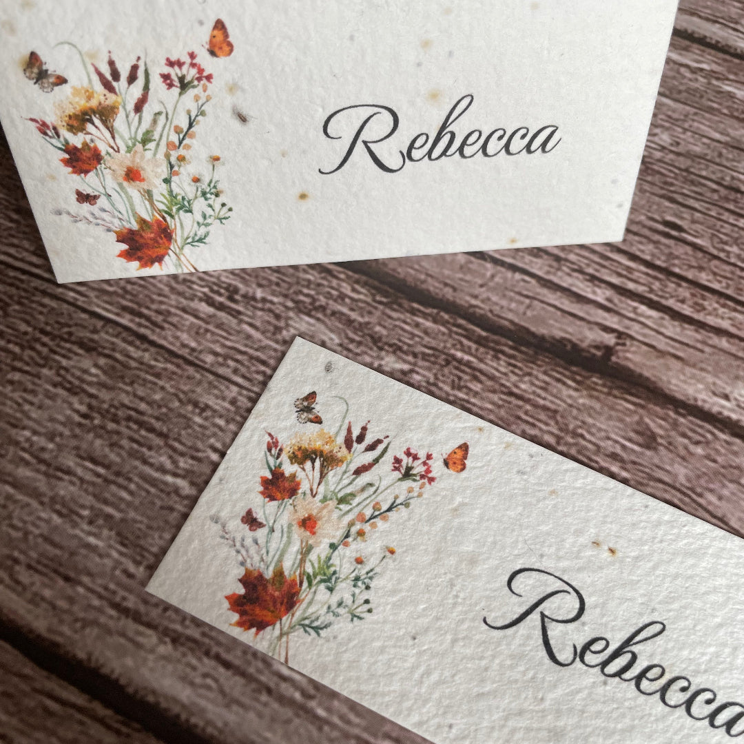 Two name cards with floral designs and 'Rebecca' printed on a wooden surface