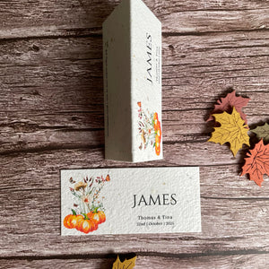 Wedding guest card with 'JAMES' branding on a wooden surface with autumn flowers and pumpkins.