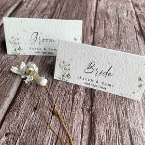 plantable seed paper wedding guest place cards in spring green theme, showing a standing close-up front view, floral design on wooden background.