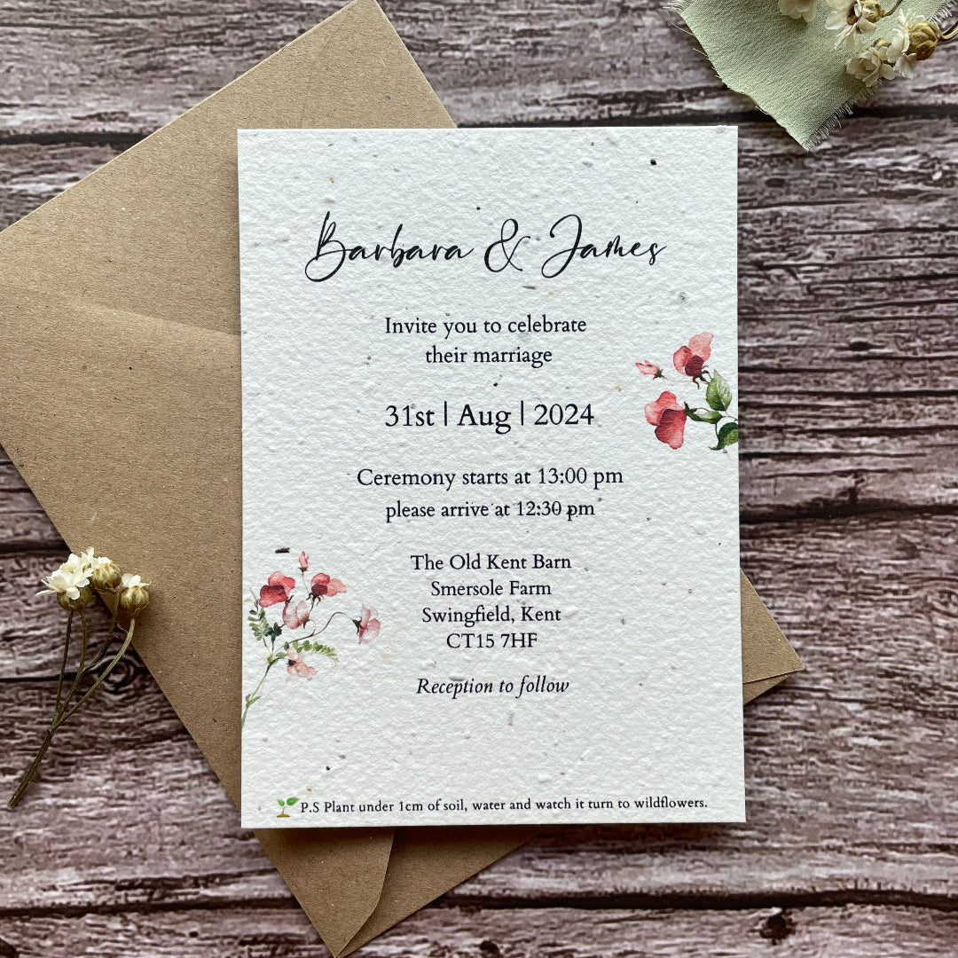 Plantable wedding invitation card with a sweet pea floral design on a wooden surface