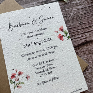 Plantable wedding invitation card with sweet pea floral designs on a wooden surface