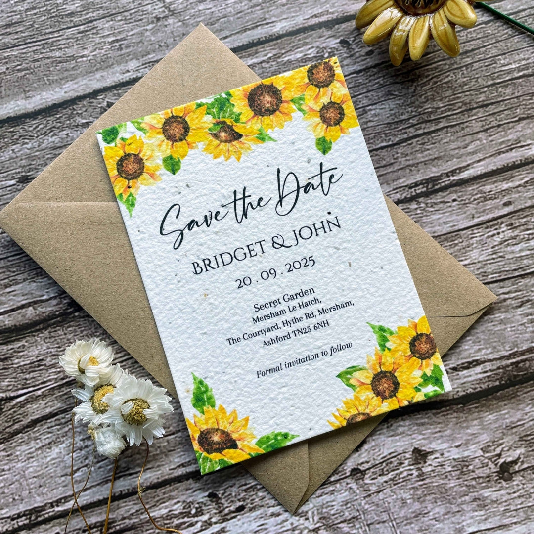 plantable seed paper wedding save the date card sunflower theme, angled view with eco-friendly brown kraft envelope, on wooden background.