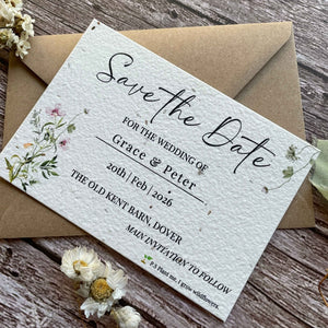 plantable seed paper wedding save the date card in spring green theme with brown kraft envelope, angled view, floral design on wooden background.