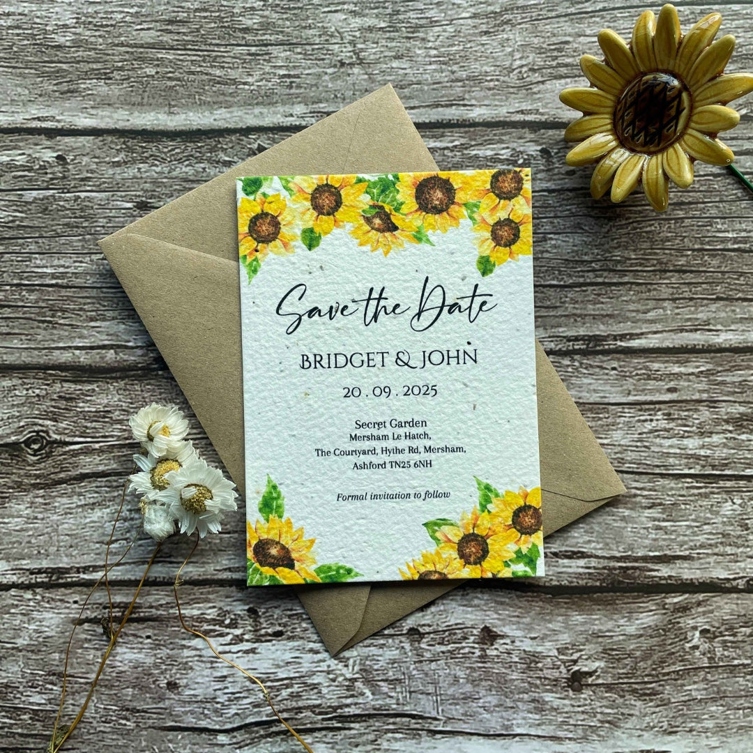 plantable seed paper wedding save the date cards in sunflowers theme, front view with eco-friendly brown kraft envelope, floral design on wooden background, alakartcreations