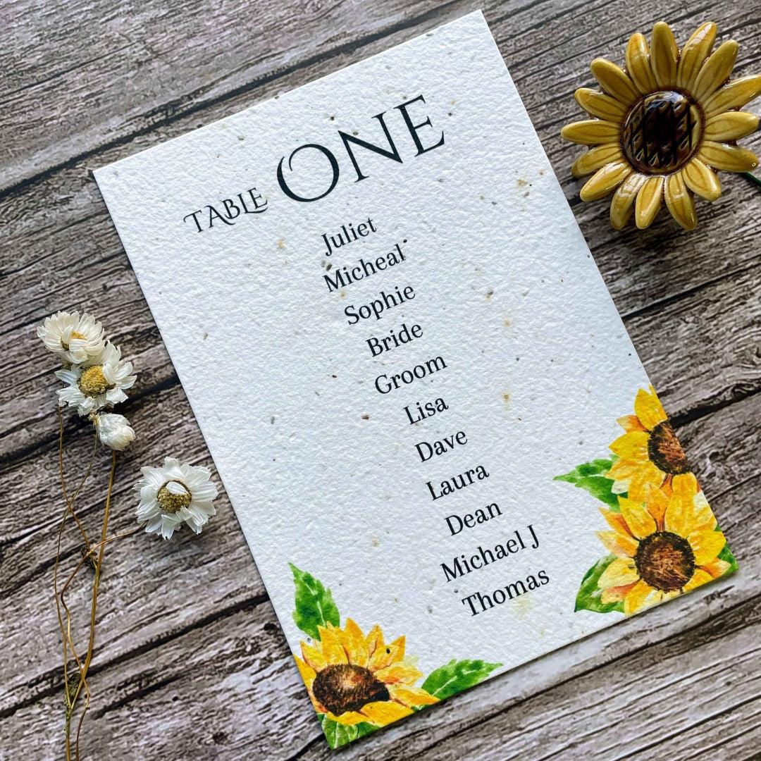 plantable seed paper wedding table seating plan in sunflowers theme, showing front angled view, floral design on wooden background, eco-friendly