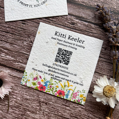 Seed paper business cards with floral design and bee illustration on a wooden surface.
