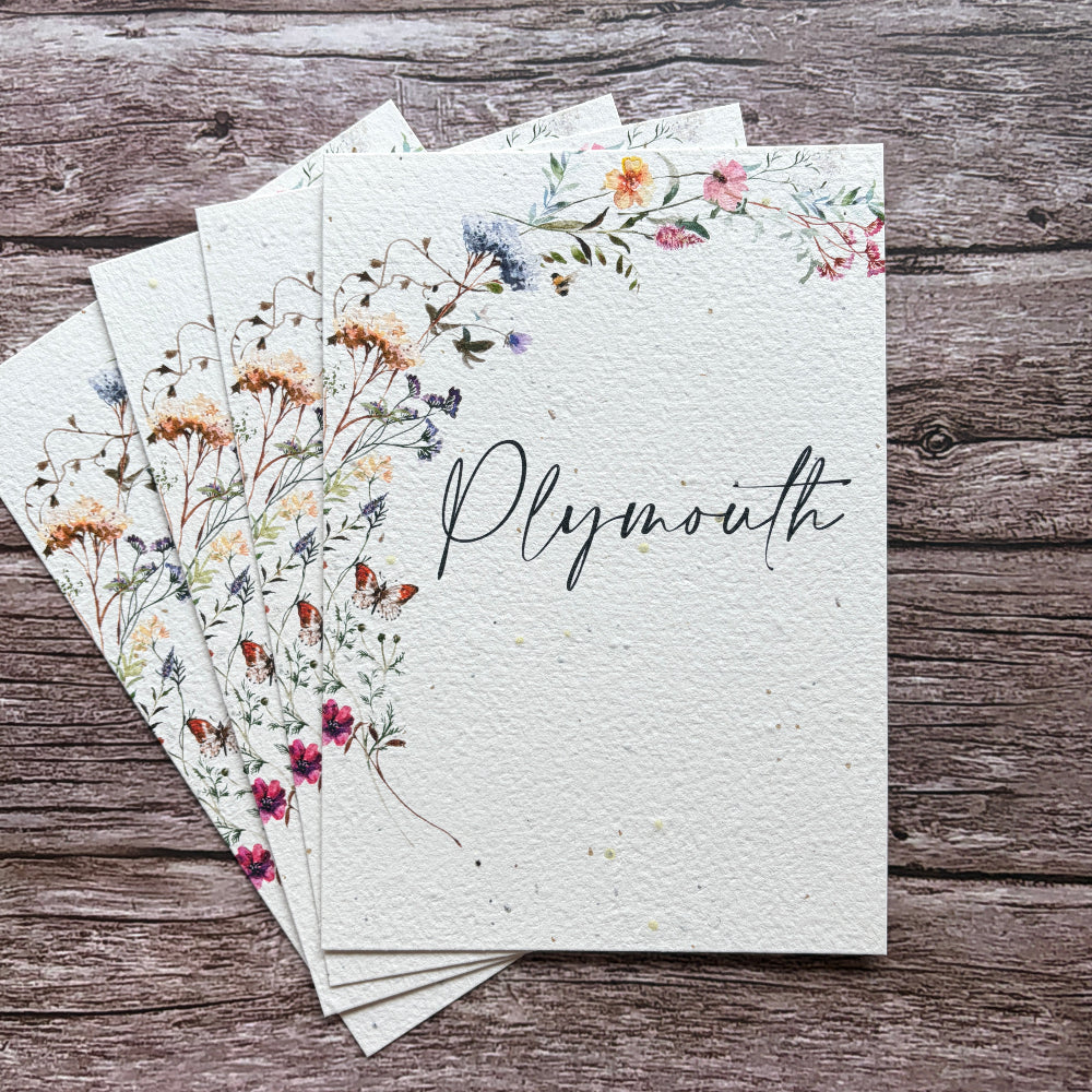 A stack of plantable paper table name cards for weddings with watercolor wildflower illustrations and the word &