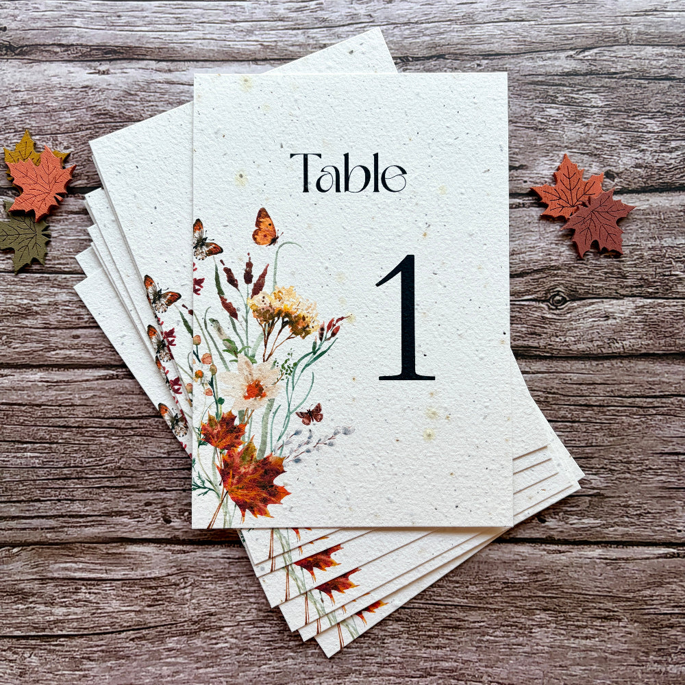 Plantable table number card with floral design on a wooden surface