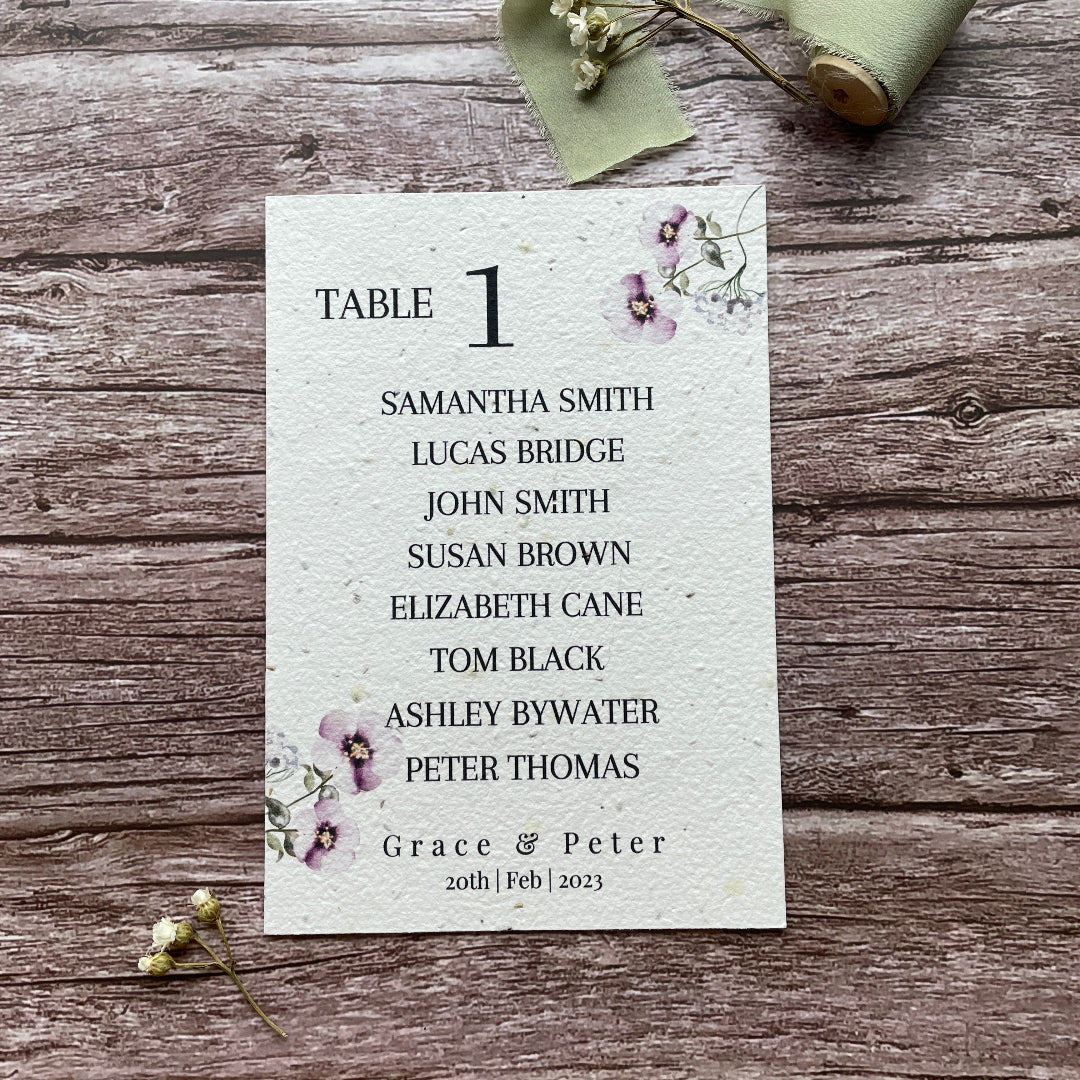 plantable seed paper seating plan cards with lilac flowers on a wooden surface