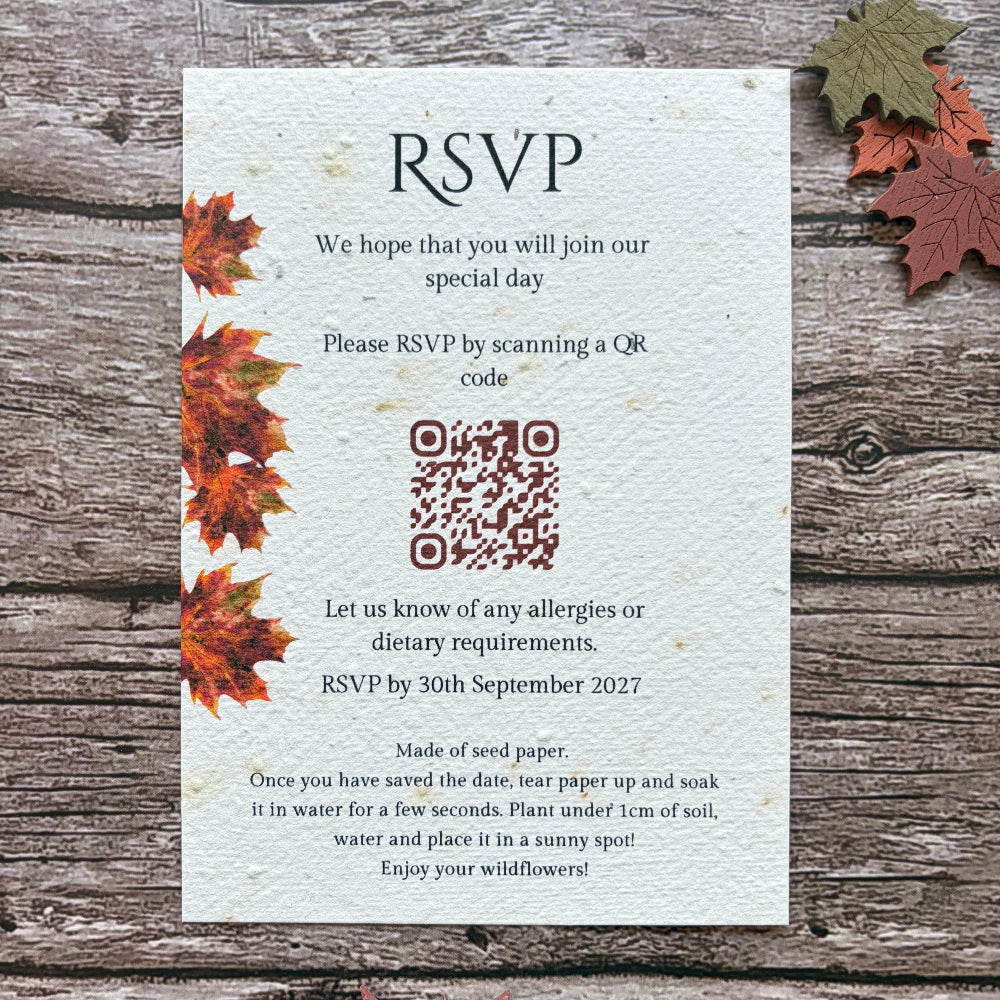 A plantable autumn wedding invite with RSVP on the back made from seed paper, styled on a rustic wooden background with autumn leaves. The card features a textured off-white paper look with printed text and a QR code.