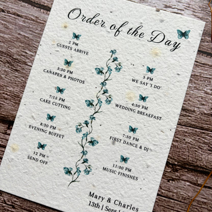 Wedding order of the day schedule with butterfly design on a wooden surface