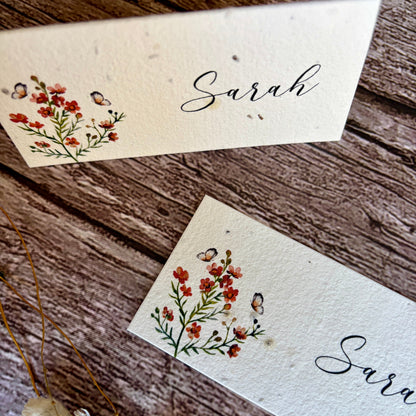 Two plantable place cards with floral designs and the name &