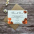 Plantable wedding Thank you card with autumn leaves design on a wooden surface with a brown envelope and white flowers.