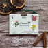 Floral plantable calendar for 2026 on a wooden surface with dried oranges and cinnamon sticks.