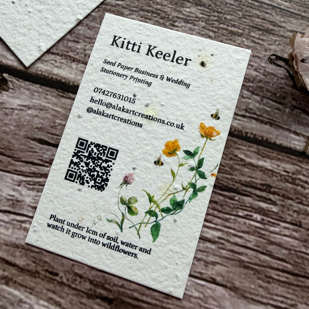 Seed paper business card with floral design and QR code on a wooden surface