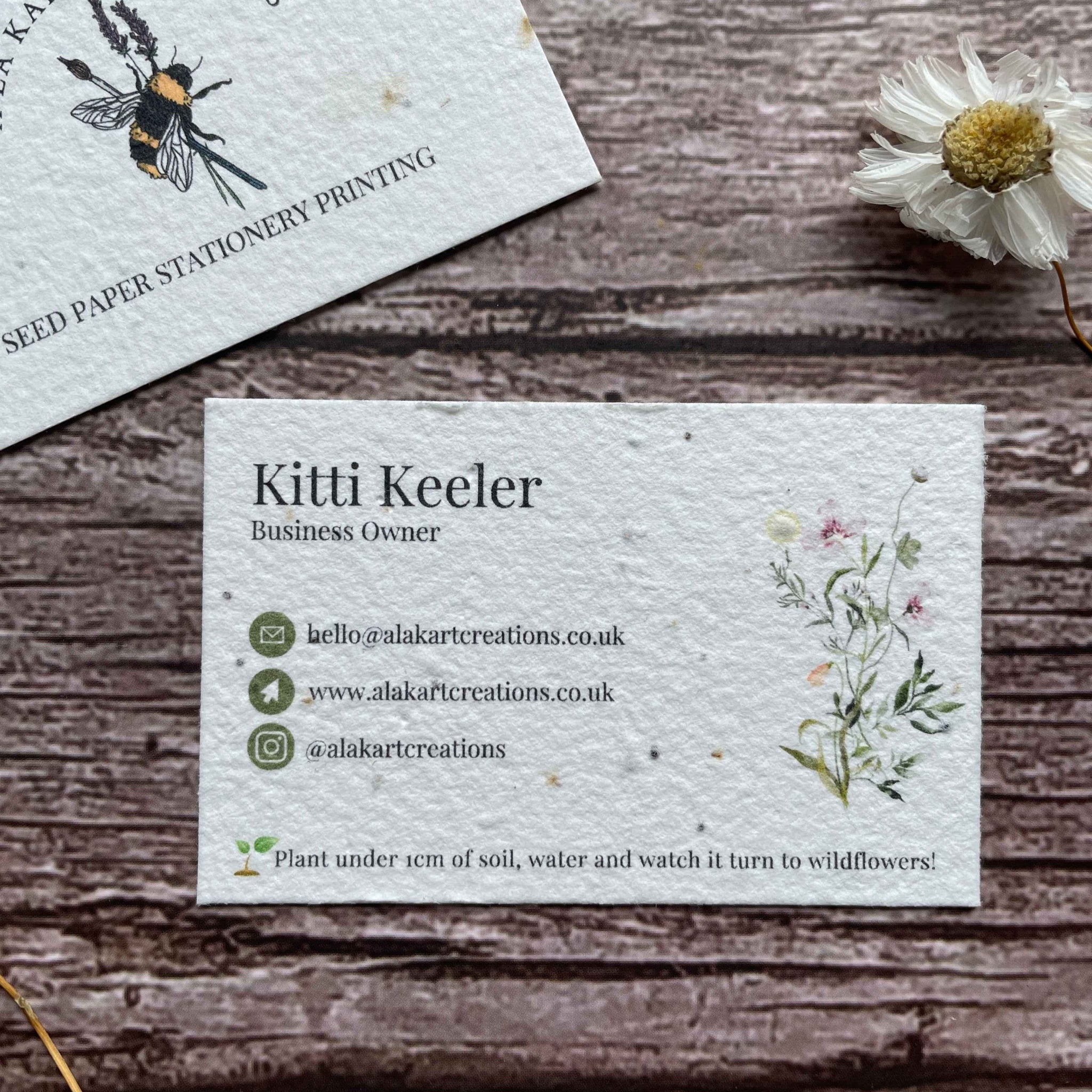 pre-designed plantable business cards with green logo and wildflowers, showcasing eco-friendly floral design and sustainable branding, alakartcreations