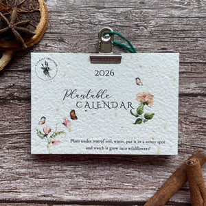 Plantsable calendar for 2026 on a wooden surface with cinnamon sticks and dried oranges.