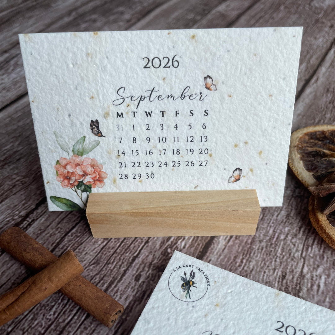 2026 calendar on a wooden stand with cinnamon sticks and dried leaves.