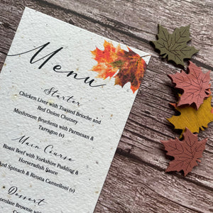 Seed paper wedding Menu card with autumn leaf design on a wooden surface close up