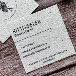 square plantable seed paper business cards with wildflower seeds, angled left showing a closeup of the custom information, from a la kart creations