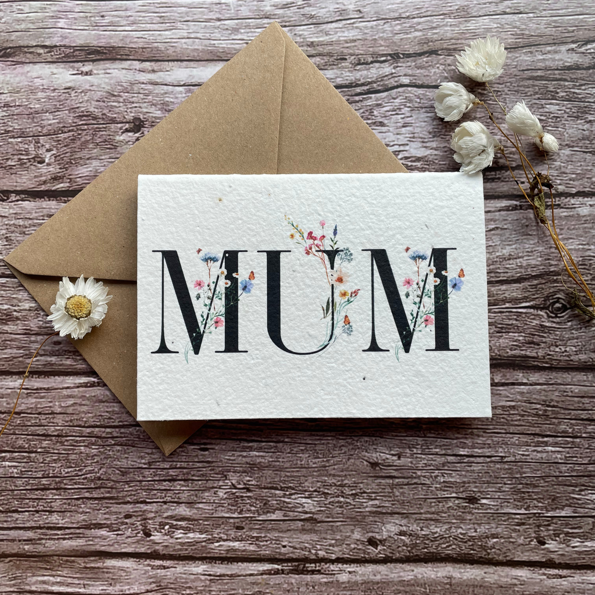 personalised plantable mother's day card with the word "mum" entwined with wildflowers, handmade from seed paper. front view.
