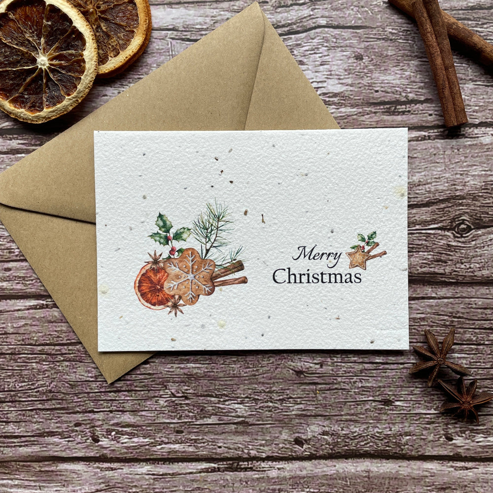 Plantable Christmas greeting card with a watercolor illustration of gingerbread, cinnamon sticks, and greenery, reading &