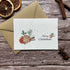 Plantable Christmas greeting card with a watercolor illustration of gingerbread, cinnamon sticks, and greenery, reading &