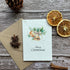 A personalized plantable Christmas card with a design of a golden bell tree, accompanied by an envelope and two whole lemons on a wooden surface.