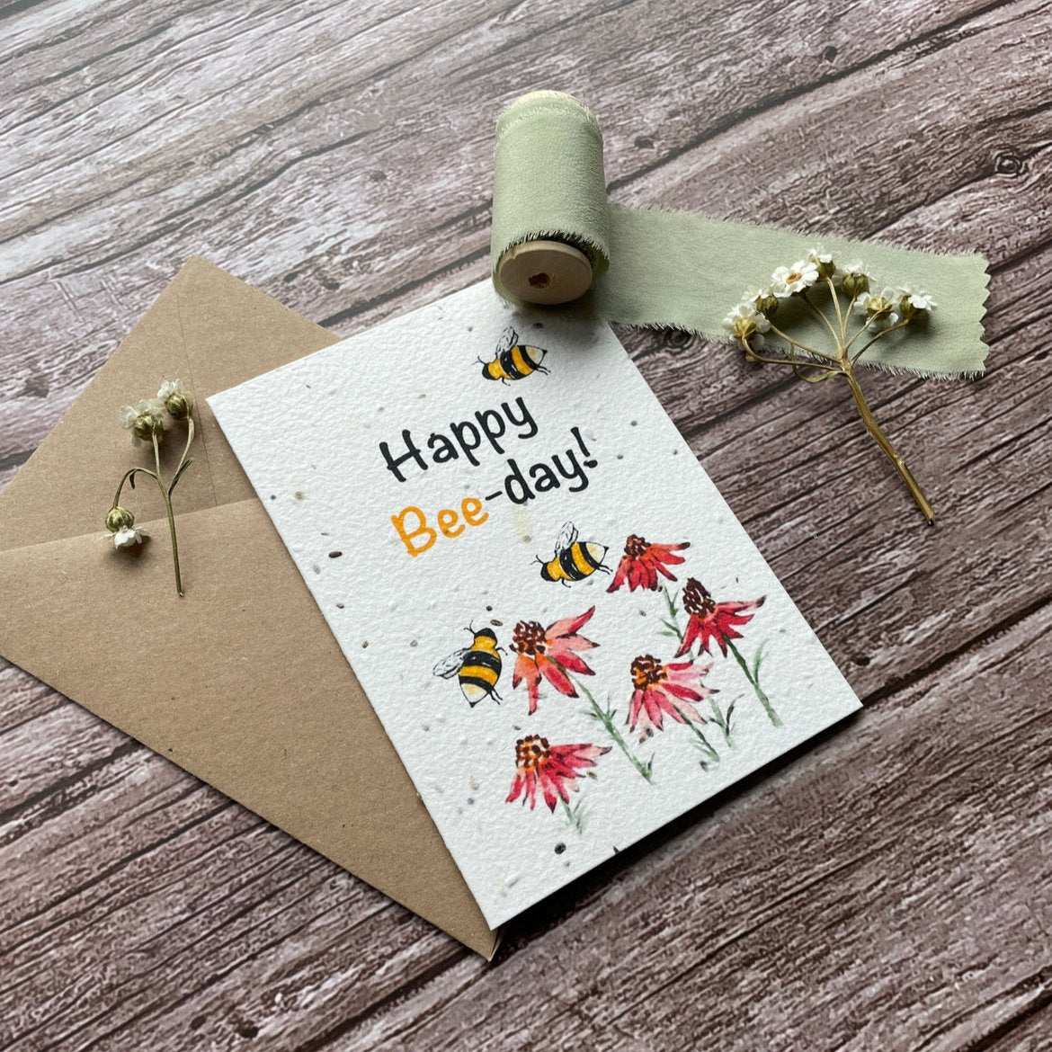 angled view of personalised happy bee day plantable birthday card with bees buzzing around wildflowers, perfect for birthday celebrations