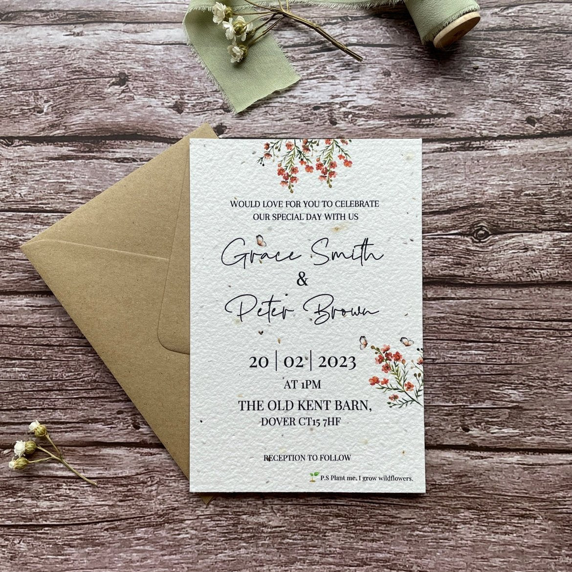 personalised plantable wedding invitations, burnt orange theme, front view with eco-friendly brown kraft envelope, floral design on wooden background