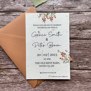 personalised plantable wedding invitations in burnt orange theme, showing front view with colour matched envelope, floral design on wooden background