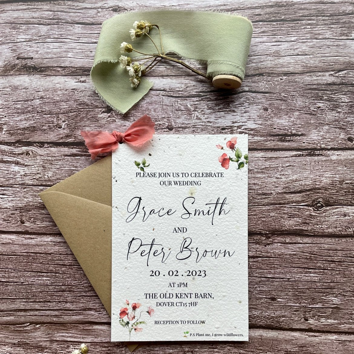 personalised plantable wedding invitations in sweet pea theme, front view with eco-friendly brown kraft envelope, floral design on wooden background